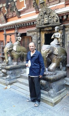 Ravi Kaka standing in front of metal elephant statues at the Golden Temple near Patan Durbar Square.  